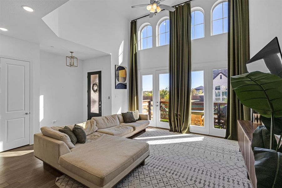 Living room with french doors, recessed lighting, a ceiling fan, a high ceiling, and wood finished floors