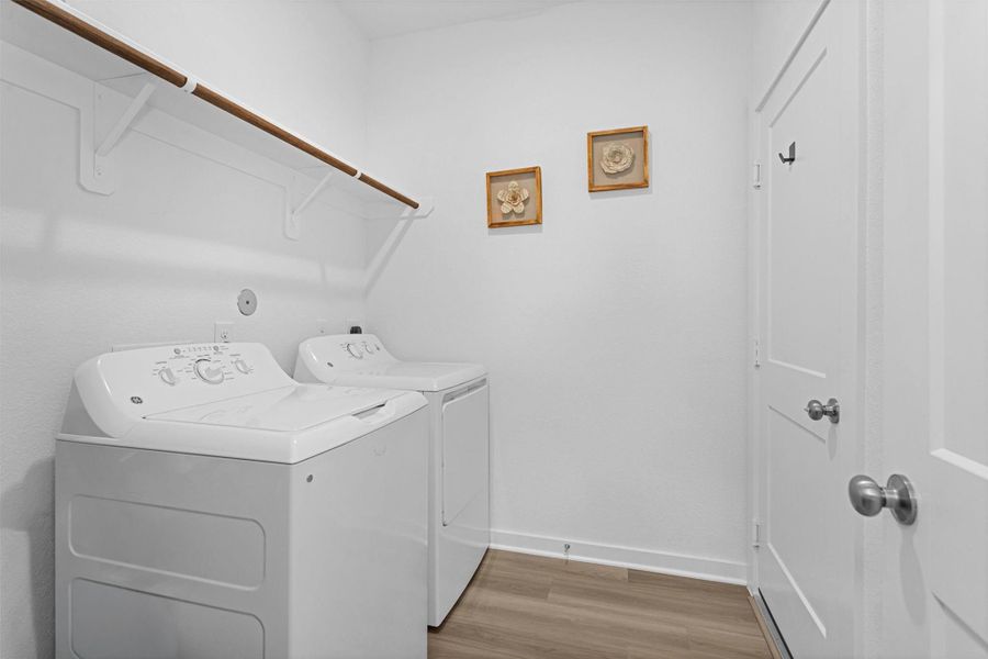 This first-floor utility room features full-size washer and dryer connections, built-in shelving, and direct access to the garage for added convenience.