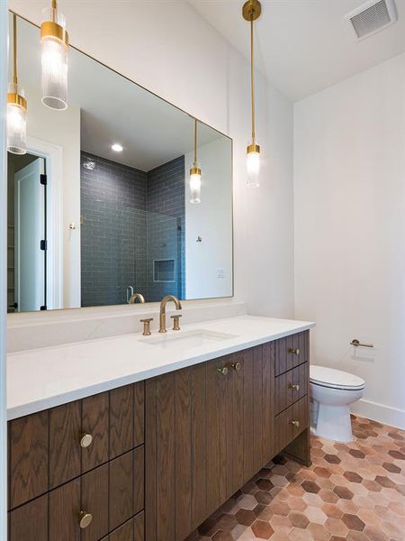 One of the secondary bathrooms features clean-lined, stained cabinets with earth tone floor tiles and decorator lighting.