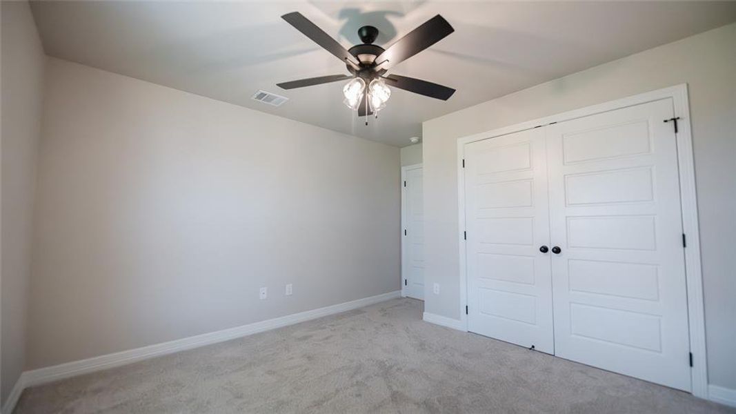 Unfurnished bedroom with light carpet, a closet, and ceiling fan Unfurnished bedroom with light carpet, a closet, and ceiling fan