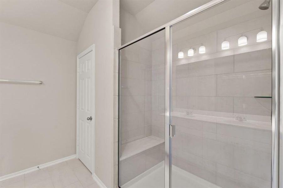 This additional view of your primary bathroom features tile flooring, fresh paint, and a large walk-in shower.