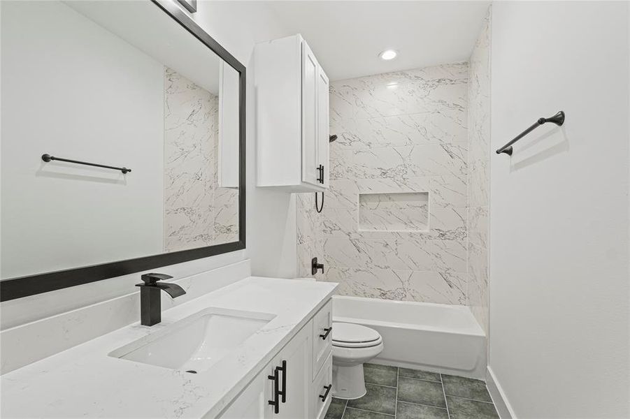 Full bathroom featuring tile patterned flooring, vanity, toilet, and tiled shower / bath combo