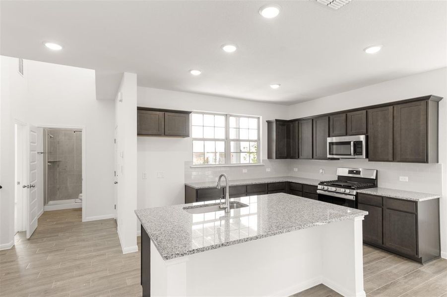 Kitchen featuring a sink, dark brown cabinets, appliances with stainless steel finishes, and wood tiled floor