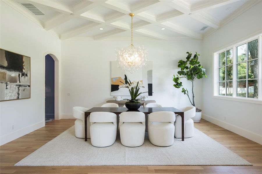 Dining space featuring coffered ceiling, a notable chandelier, wood flooring, and beamed ceiling