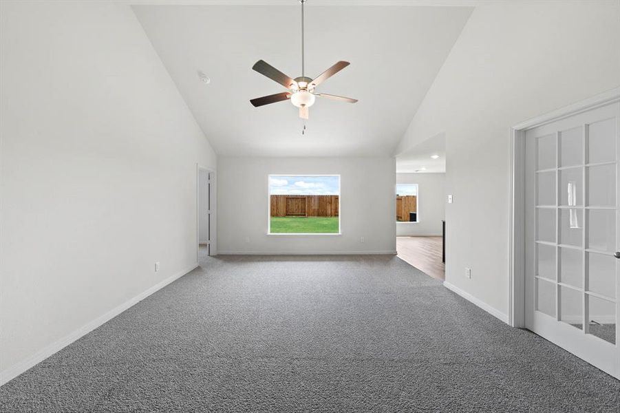 Unfurnished living room featuring high vaulted ceiling, carpet, and ceiling fan Unfurnished living room featuring high vaulted ceiling, carpet, and ceiling fan