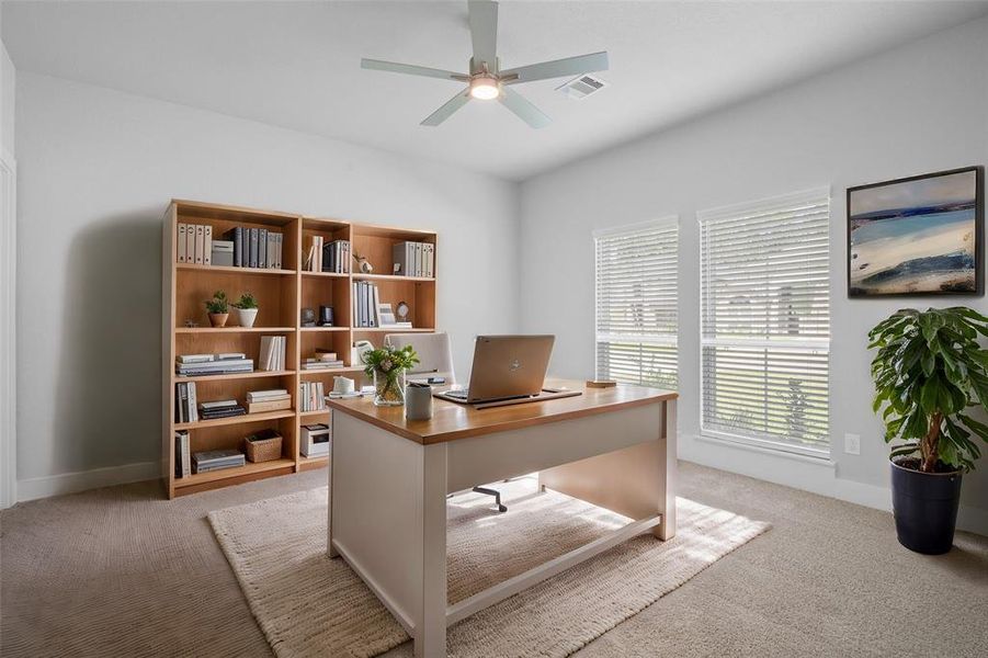 Quietly nestled in front of the home is the handsome home office. Featuring high ceilings, ceiling fan with lighting, custom paint, plush carpet flooring, and large windows with privacy blinds.