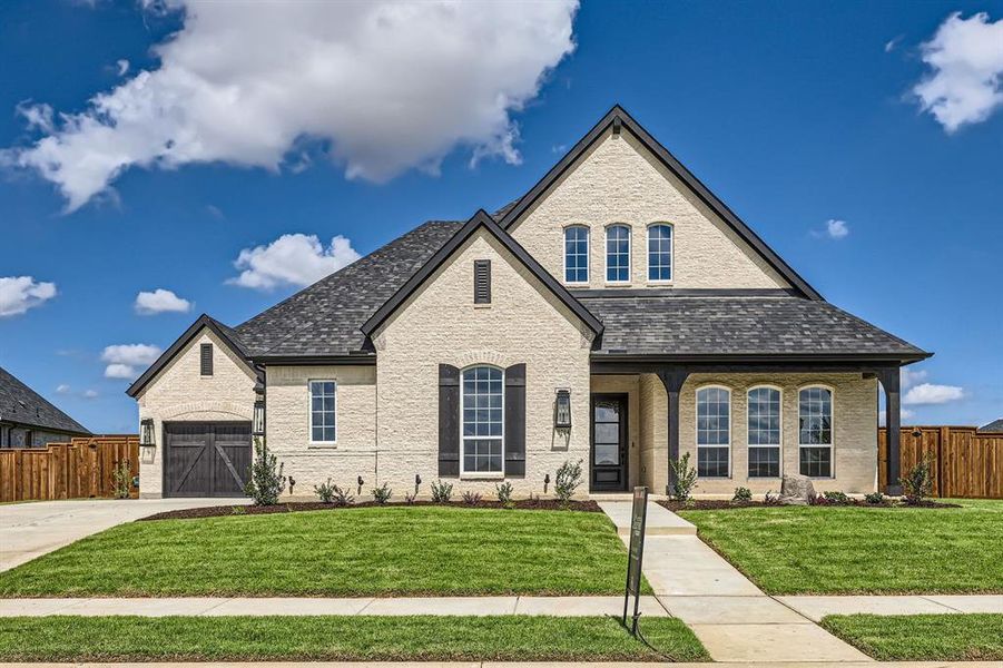 French provincial home featuring a garage and a front yard