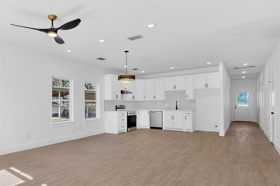 Kitchen with light countertops, appliances with stainless steel finishes, white cabinetry, a chandelier, and recessed lighting