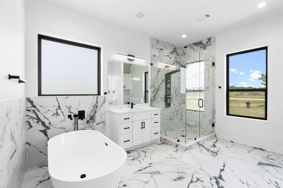 Full bath featuring a freestanding bath, recessed lighting, vanity, a marble finish shower, and marble tiled flooring Full bath featuring a freestanding bath, recessed lighting, vanity, a marble finish shower, and marble tiled flooring