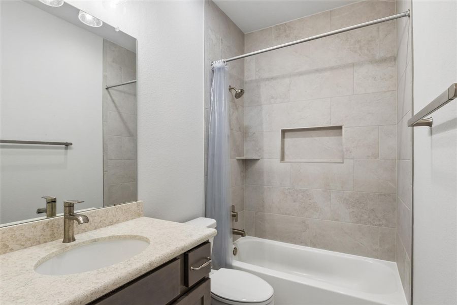 A well-appointed bathroom features a single vanity, a sleek mirror, and a combined shower-bathtub.