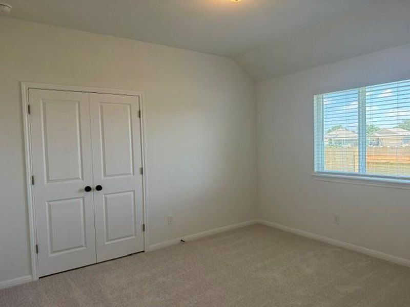 Neutral paint palette bedroom featuring carpet flooring, a window with blinds, and double-panel closet doors with dark hardware