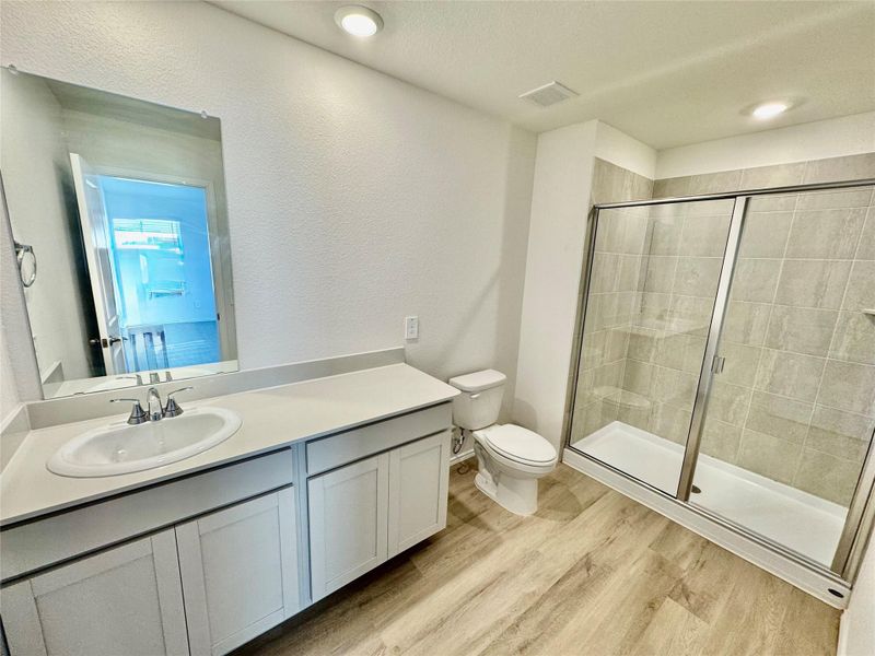 Full bathroom featuring vanity, light wood-style floors, a textured wall, and a stall shower Full bathroom featuring vanity, light wood-style floors, a textured wall, and a stall shower