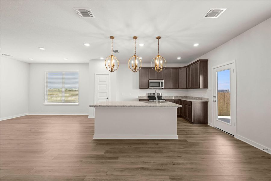 A spacious kitchen with a large island and ample cabinet space seamlessly flows into a luminous living area.