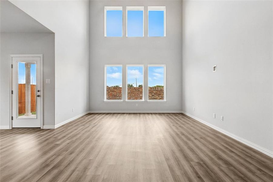 Unfurnished living room featuring wood finished floors and a high ceiling Unfurnished living room featuring wood finished floors and a high ceiling