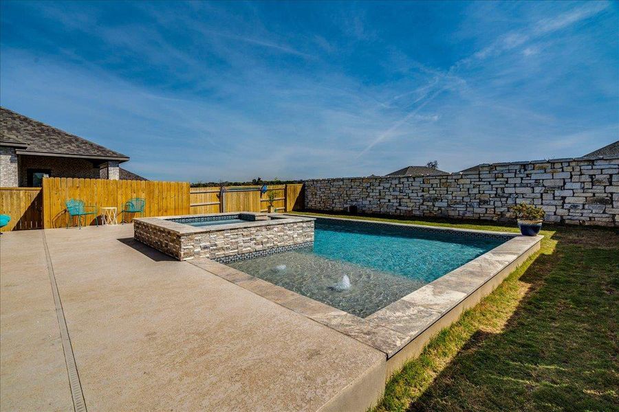 Integrated pool / hot tub featuring a patio and a fenced backyard