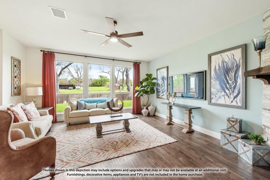 Living room with hardwood floors, ceiling fan, large windows, and stone fireplace accent wall