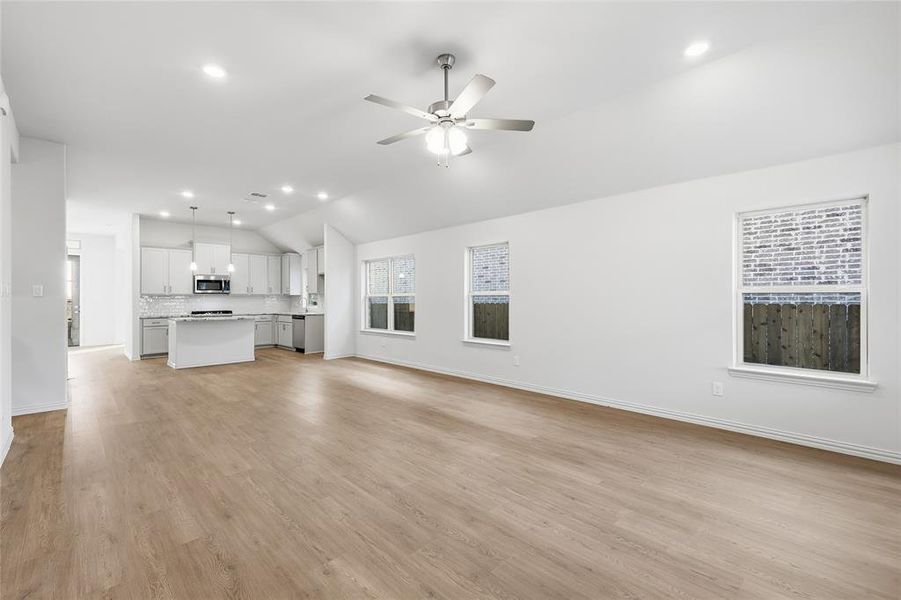 Unfurnished living room featuring ceiling fan, recessed lighting, light wood-type flooring, and vaulted ceiling Unfurnished living room featuring ceiling fan, recessed lighting, light wood-type flooring, and vaulted ceiling