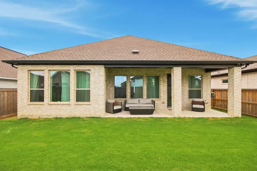Inviting brick residence offering a generous covered patio overlooking a lush, expansive backyard.