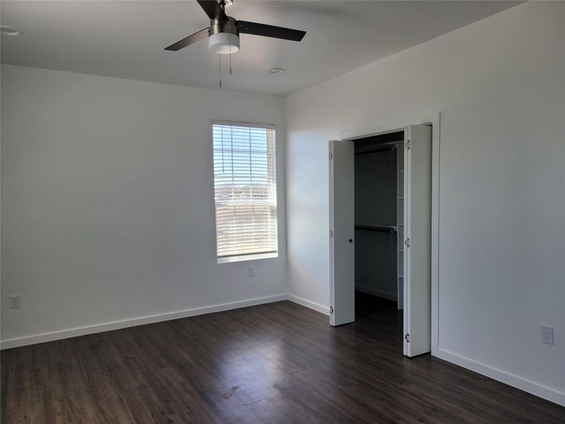 A well-lit bedroom features rich wood flooring and a convenient walk-in closet.