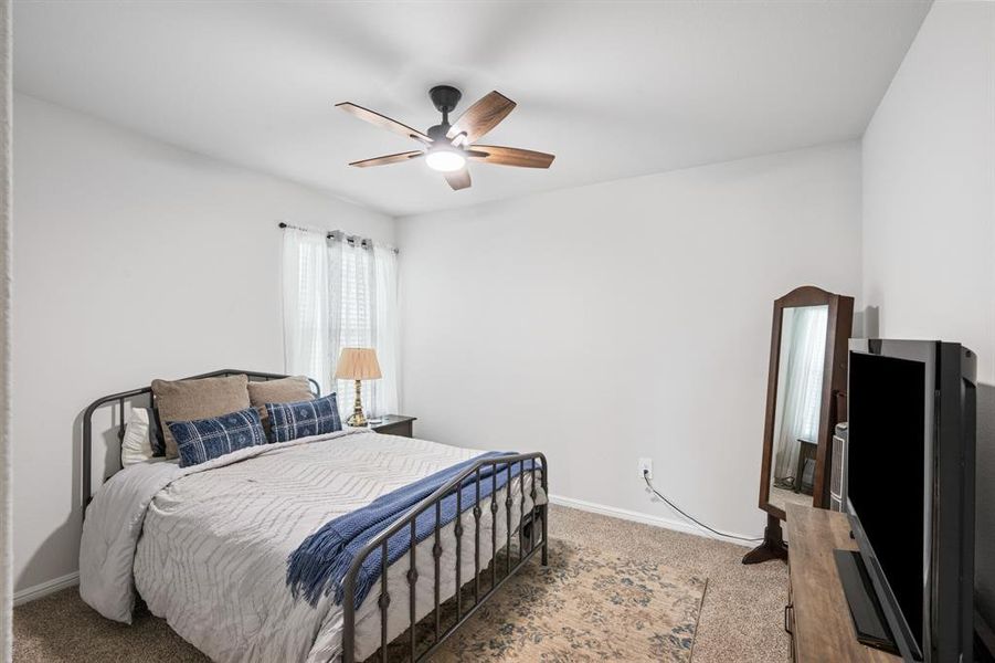 Carpeted bedroom with ceiling fan and baseboards