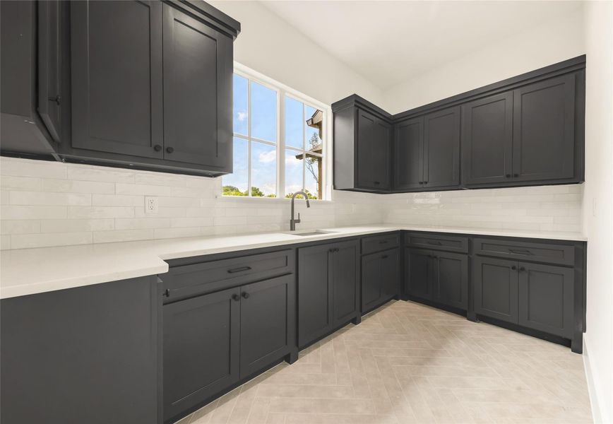 Kitchen featuring decorative backsplash, dark cabinets, and light stone counters