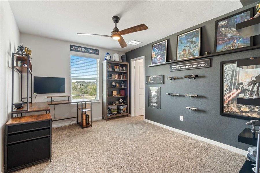 Carpeted office space featuring baseboards, visible vents, and a ceiling fan