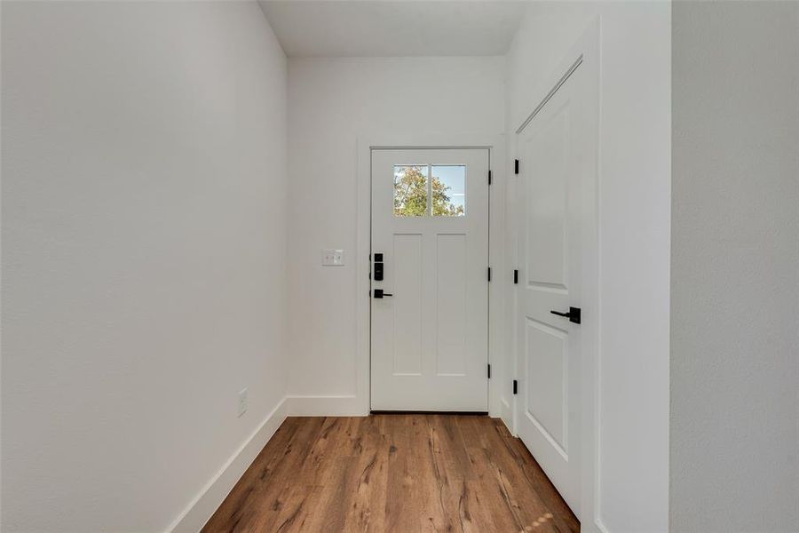 Doorway to outside featuring wood finished floors and baseboards Doorway to outside featuring wood finished floors and baseboards