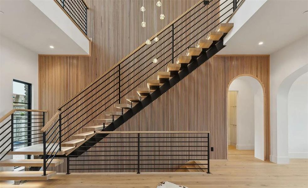 Stairs with wooden walls, recessed lighting, a high ceiling, wood finished floors, and an accent wall