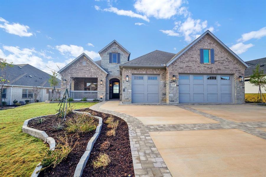 View of front of property featuring driveway, brick siding, roof with shingles, a front lawn, and an attached garage