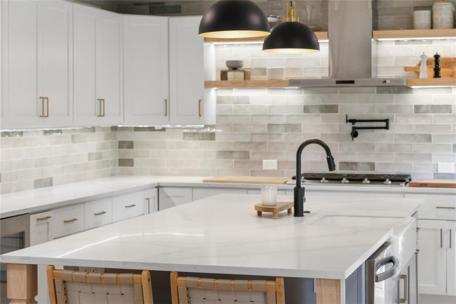 Kitchen with white cabinets, decorative backsplash, light stone countertops, wine cooler, and open shelves
