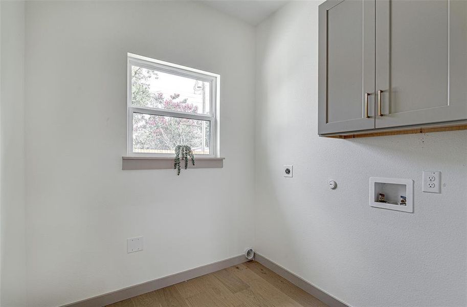 Laundry room with cabinet space, light wood finished floors, hookup for an electric dryer and washer hookup