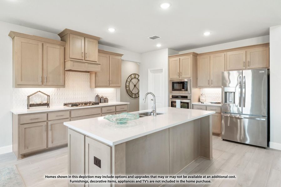Kitchen with light wood cabinets, center island with sink, white countertops, and stainless steel appliances