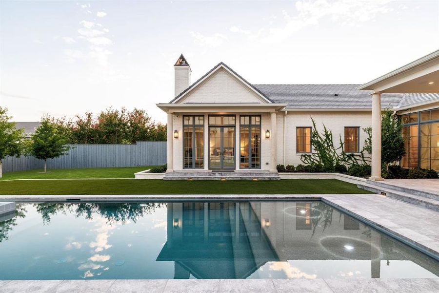 Rear view of property with a patio area, a chimney, brick siding, and french doors Rear view of property with a patio area, a chimney, brick siding, and french doors