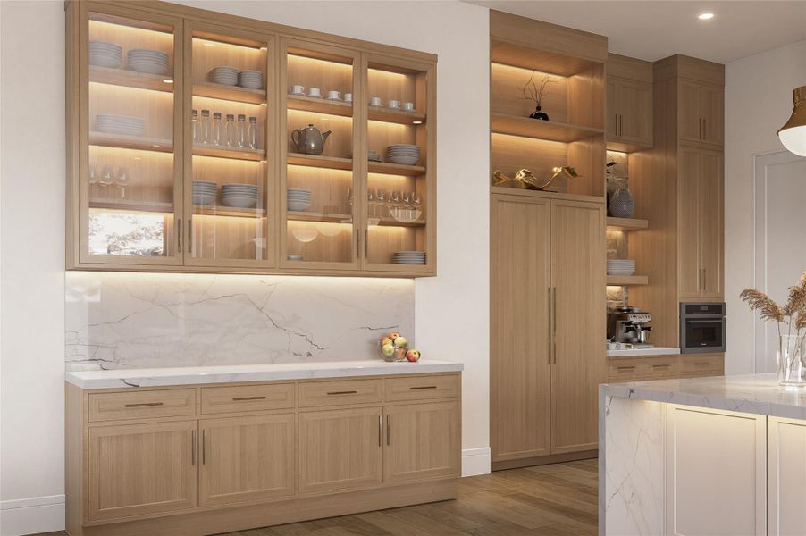 This wall of cabinetry blends visual clarity with practical design. With soft underlighting, natural wood finishes, and glass-front upper cabinets, the space balances display and storage with ease. A marble-look backsplash adds texture and elegance, creating a kitchen environment both polished and purposeful.