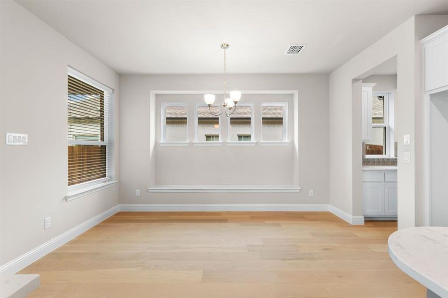 Unfurnished dining area featuring a chandelier and light hardwood / wood-style floors