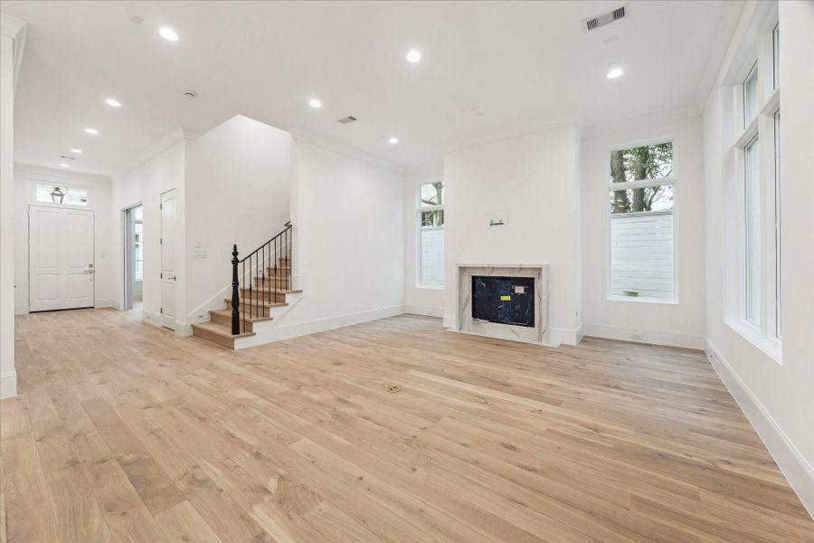 The expansive living room features an elegant fireplace with Symphony Alto Quartz, wrought iron stairway detail, LED integrated recessed lighting and Pella Lifestyle windows.