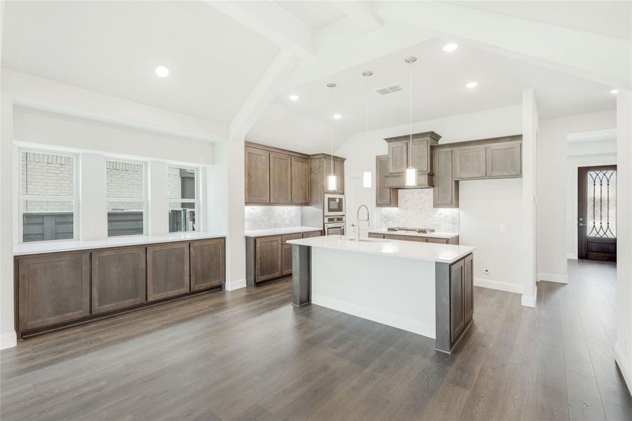 Open kitchen with dark wood cabinets, center island, white countertops, and hardwood floors Open kitchen with dark wood cabinets, center island, white countertops, and hardwood floors