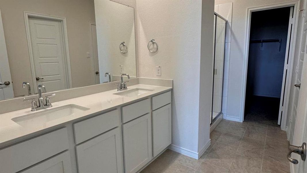 Full bathroom with a shower stall, double vanity, a walk in closet, and light tile patterned flooring Full bathroom with a shower stall, double vanity, a walk in closet, and light tile patterned flooring
