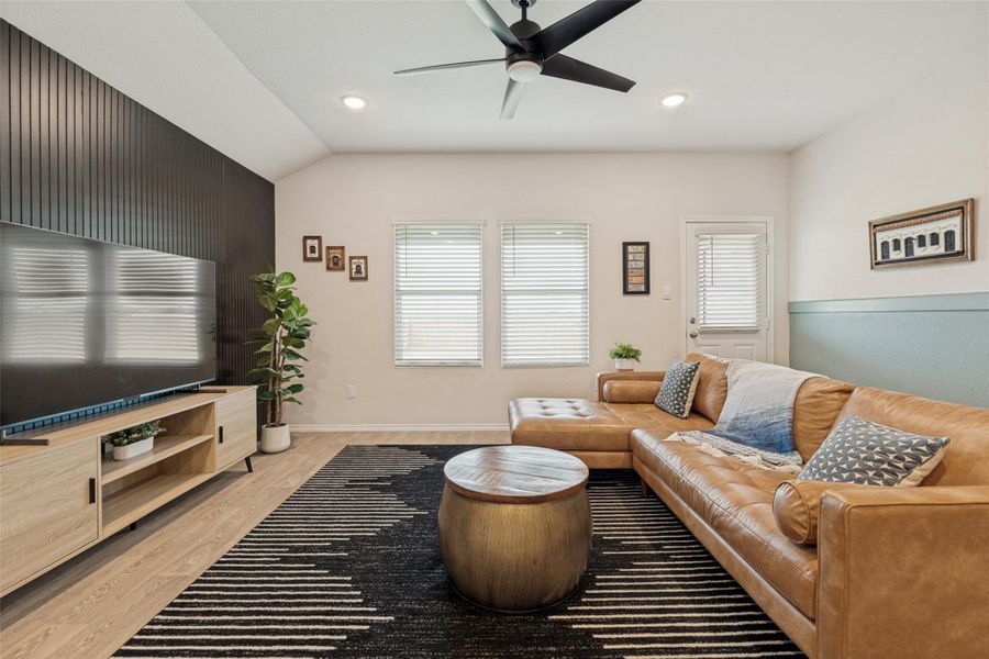 A spacious living area offers comfort with a large sectional sofa and modern ceiling fan.