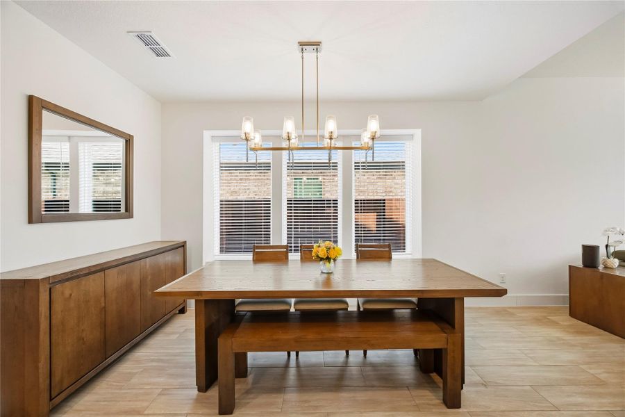 Large windows dressed with blinds bring in abundant natural light, giving the dining room a warm, inviting atmosphere with an easy sense of elegance. Large windows dressed with blinds bring in abundant natural light, giving the dining room a warm, inviting atmosphere with an easy sense of elegance.