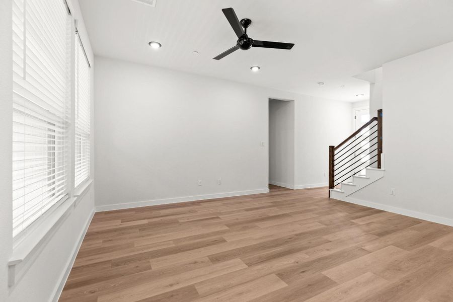 A versatile living space with light wood-tone flooring and a striking ceiling fan. A versatile living space with light wood-tone flooring and a striking ceiling fan.