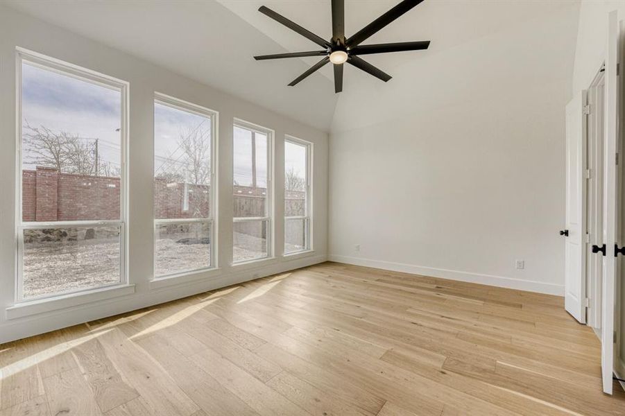Spare room with a ceiling fan, light wood finished floors, and vaulted ceiling