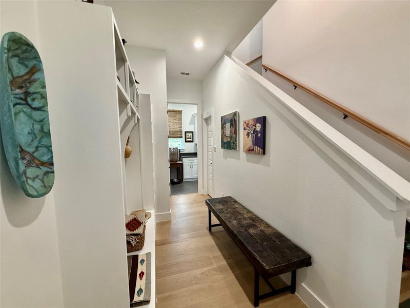 Entryway featuring wood-finish flooring, built-in shelving, and a prominent staircase with a wood handrail