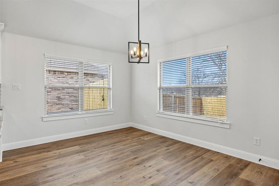 Unfurnished dining area featuring wood finished floors and a chandelier