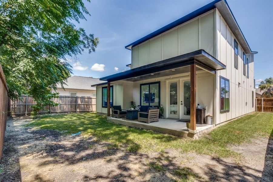 Back of house with board and batten siding, a fenced backyard, french doors, and a patio