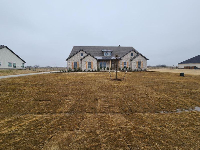 French country home with stone siding and a front yard
