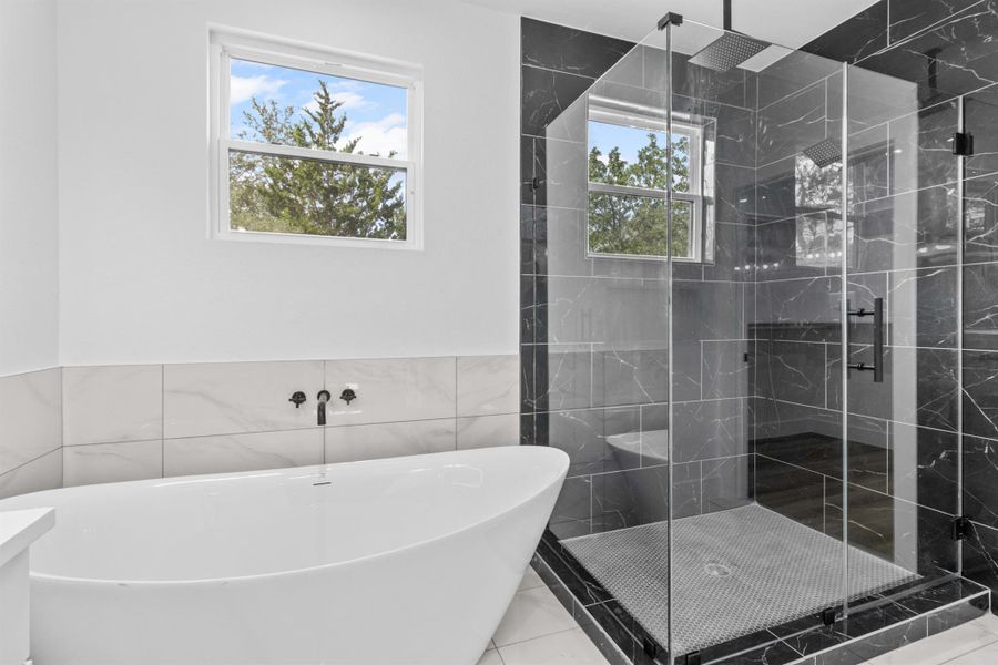 Primary bath with a marble finish shower, a freestanding bath, tile walls, and tile patterned flooring