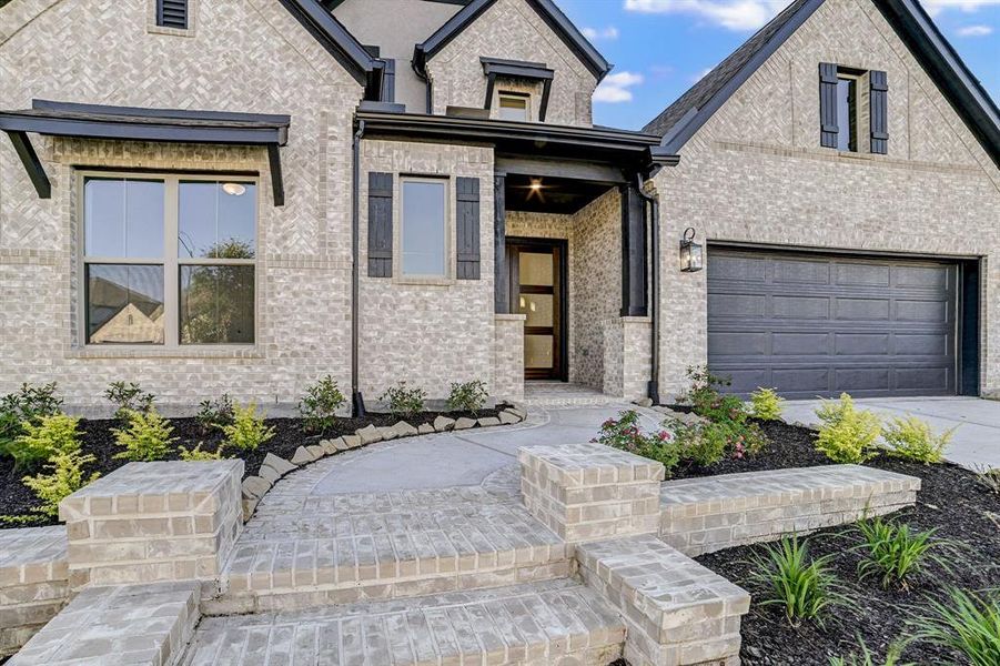 Stunning brick and stucco elevation with decorative shutter accents, carriage lights and beautiful landscaping!