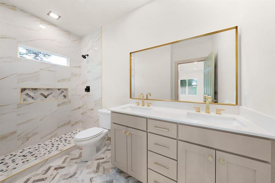 Full bathroom featuring a sink, a marble finish shower, toilet, and double vanity