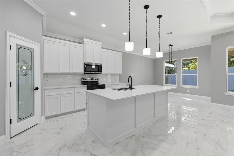 Kitchen with tasteful backsplash, ornamental molding, white cabinets, electric range, and stainless steel microwave Kitchen with tasteful backsplash, ornamental molding, white cabinets, electric range, and stainless steel microwave